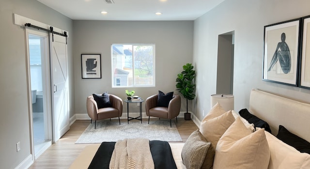 living area featuring visible vents, light wood-type flooring, a barn door, baseboards, and recessed lighting