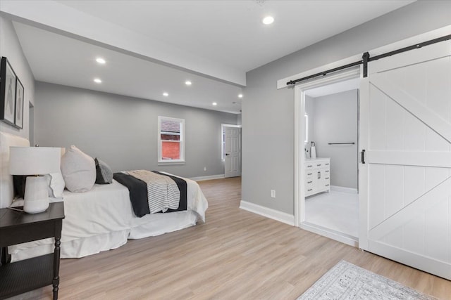 bedroom with recessed lighting, baseboards, a barn door, and light wood-style flooring