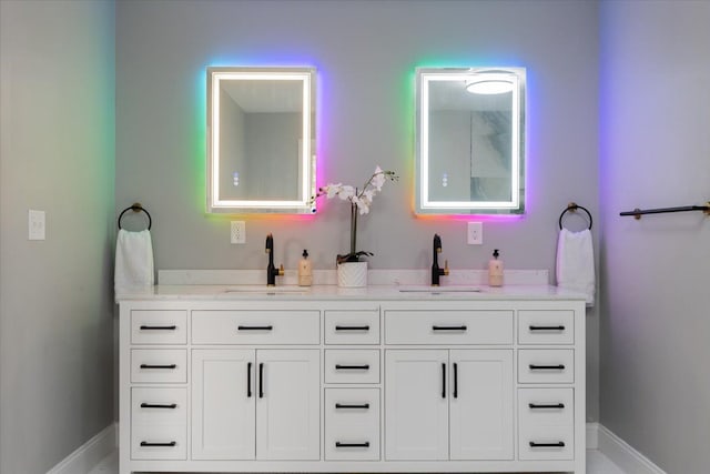 bathroom featuring double vanity, baseboards, and a sink