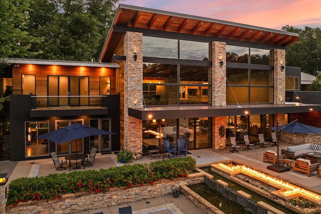 10463 W H Ave, Kalamazoo, MI 49009 - back of house featuring stone siding, a fire pit, a balcony, and a patio area