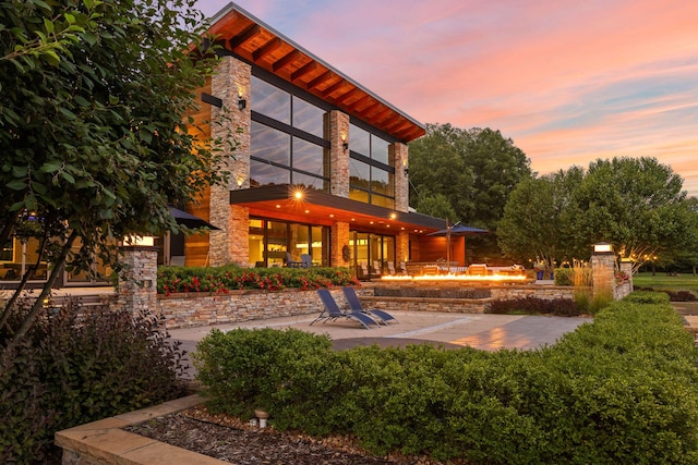 10463 W H Ave, Kalamazoo, MI 49009 - back of house at dusk with a patio, an outdoor fire pit, and stone siding