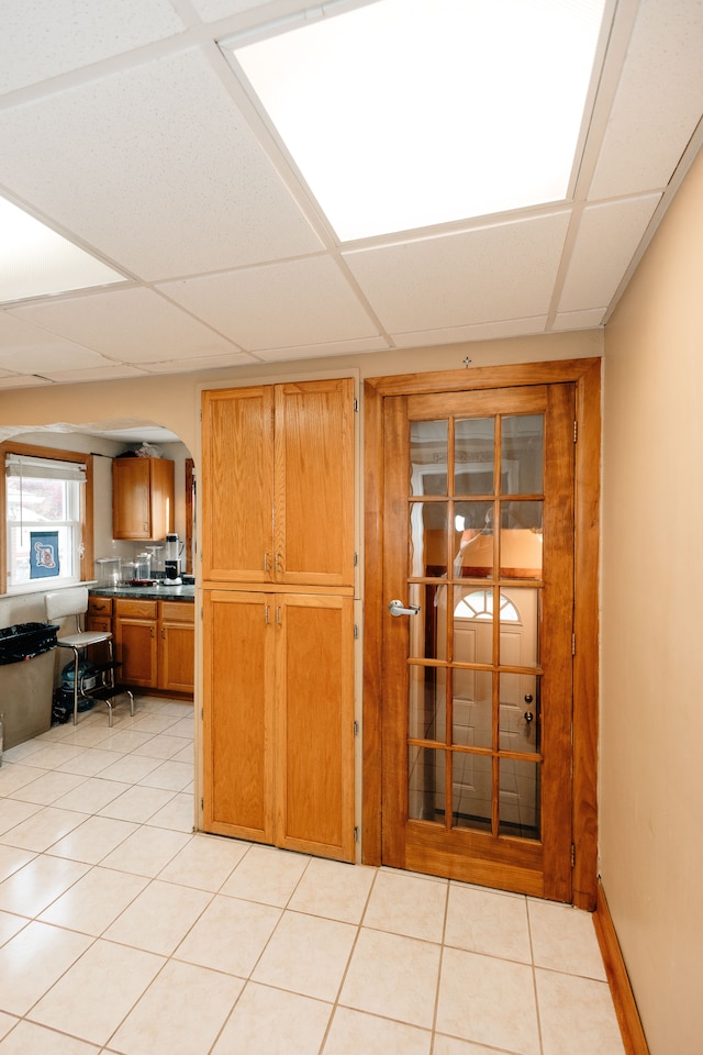 15261 Demean Ave, Allen Park, MI 48101 - kitchen with arched walkways, brown cabinets, a paneled ceiling, light tile patterned flooring, and dark countertops