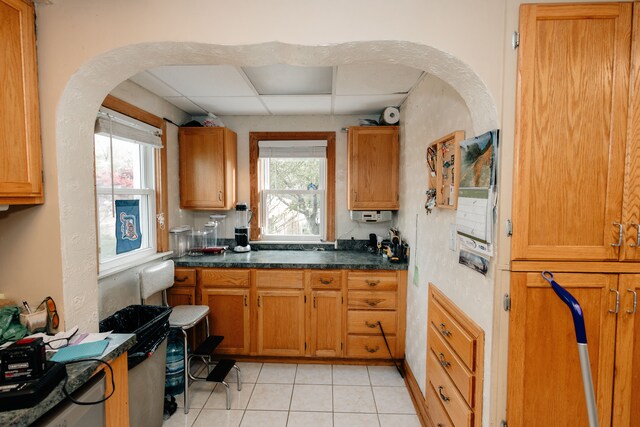 15261 Demean Ave, Allen Park, MI 48101 - kitchen featuring dark countertops, light tile patterned floors, brown cabinetry, a drop ceiling, and arched walkways