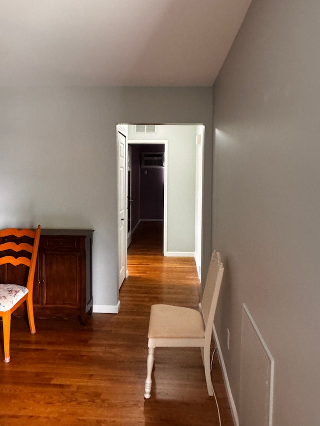 hallway featuring baseboards, wood finished floors, and visible vents