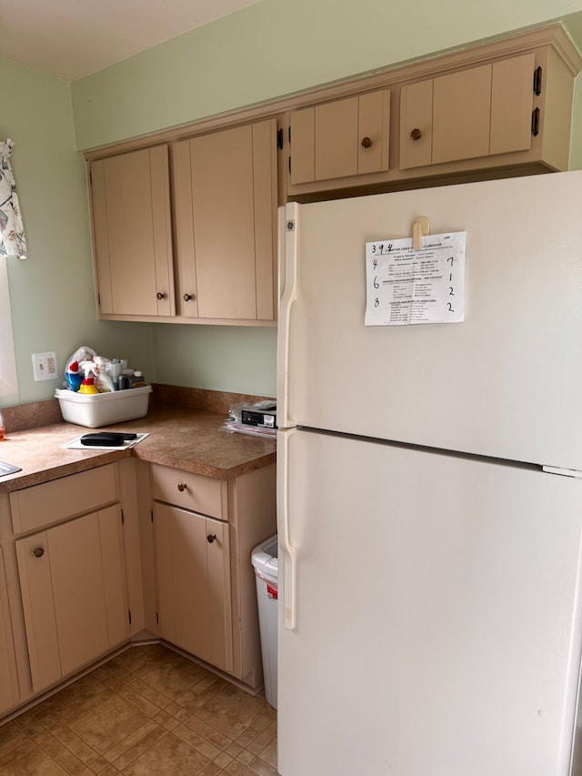 kitchen with freestanding refrigerator and cream cabinets