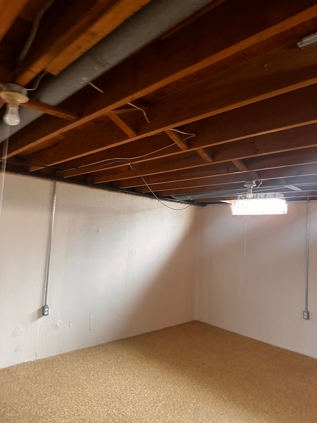 below grade area with ceiling fan and carpet flooring