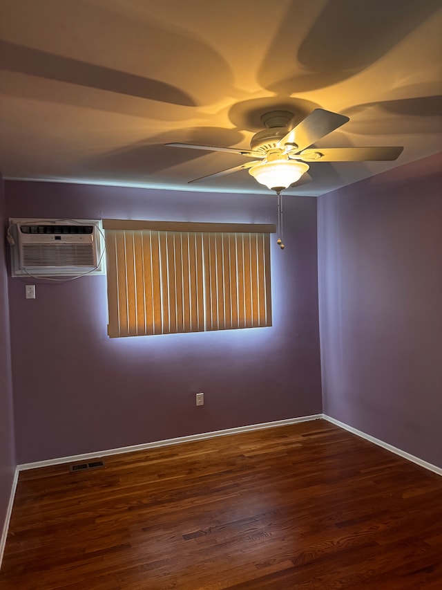 empty room with visible vents, wood finished floors, baseboards, a wall mounted air conditioner, and ceiling fan