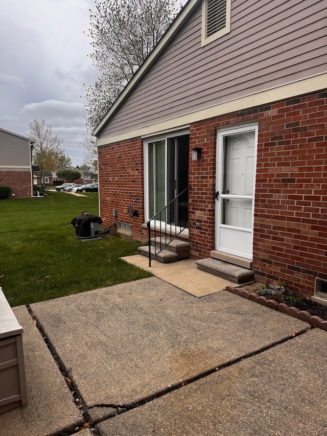 back of house featuring entry steps, a yard, a patio area, and brick siding