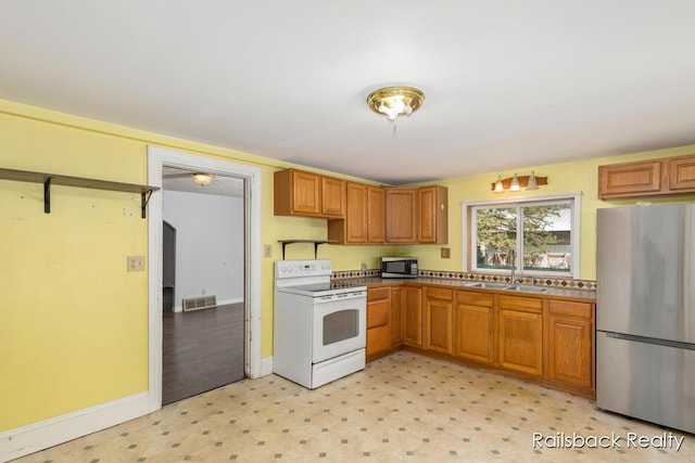 kitchen featuring visible vents, appliances with stainless steel finishes, a sink, baseboards, and light floors