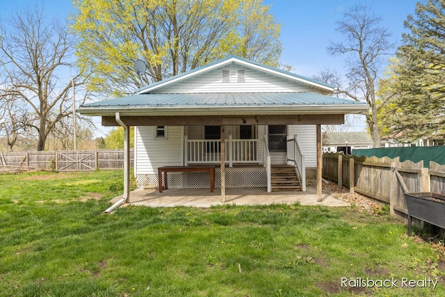 view of front of property featuring a fenced backyard, a patio area, metal roof, and a front yard