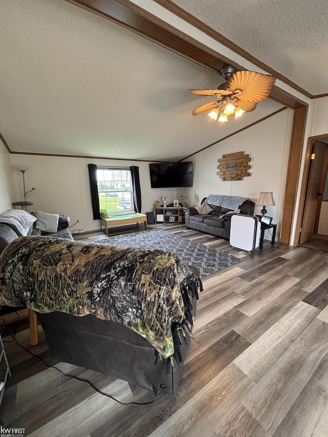 bedroom with vaulted ceiling with beams, a textured ceiling, a ceiling fan, and wood finished floors