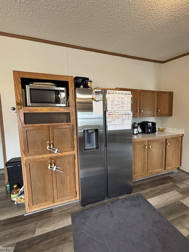 kitchen featuring crown molding, stainless steel appliances, a textured ceiling, and dark wood-type flooring