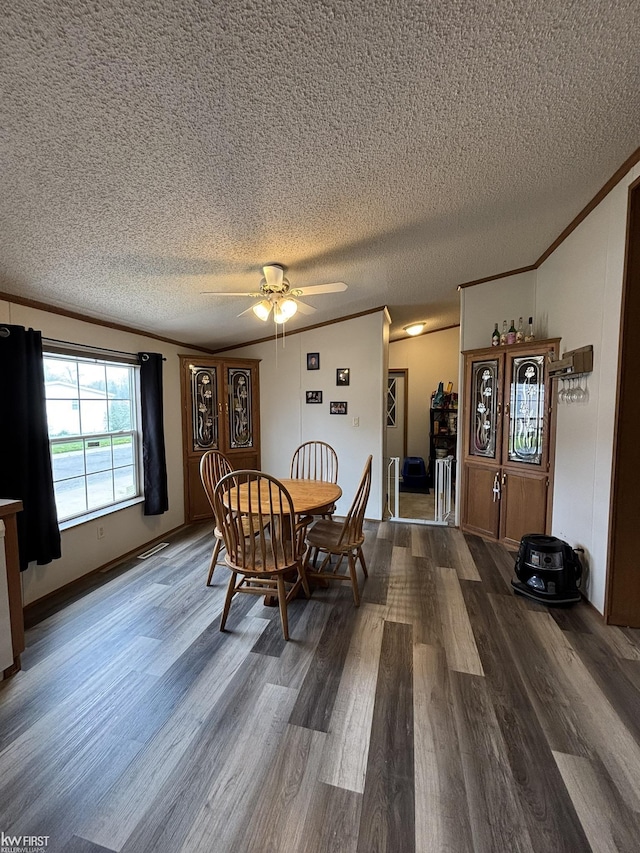 dining area with ceiling fan, ornamental molding, a textured ceiling, and dark wood-type flooring