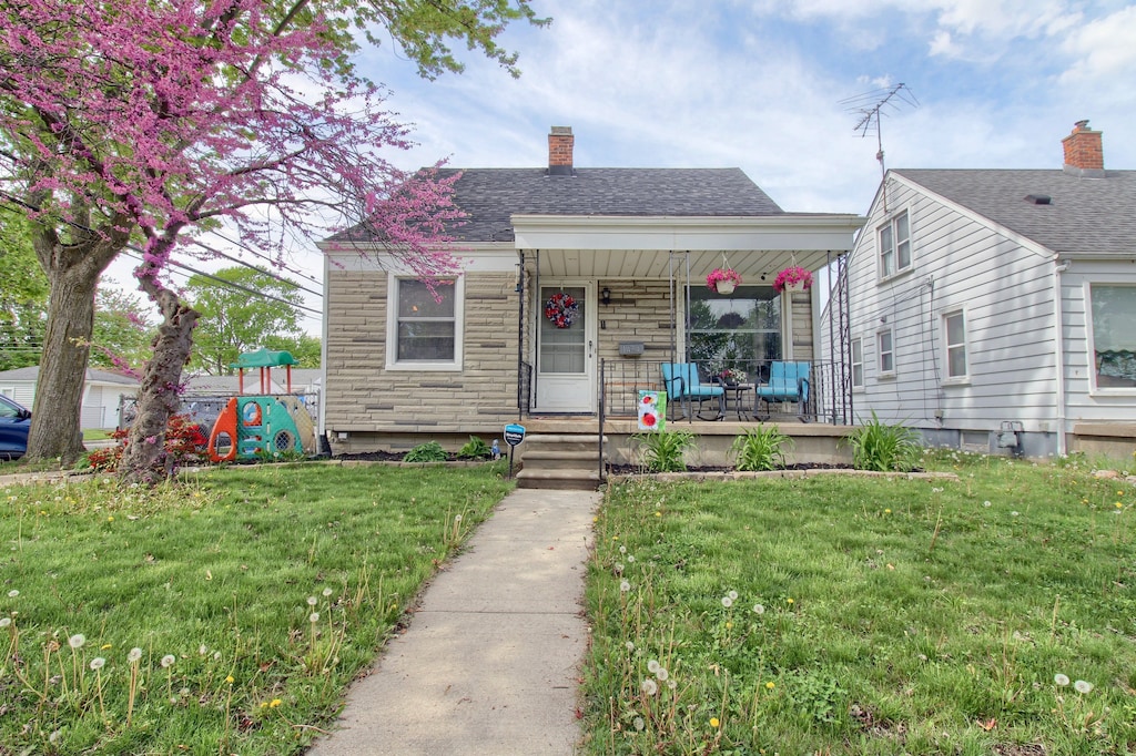 bungalow-style house with a porch, a front yard, and a chimney