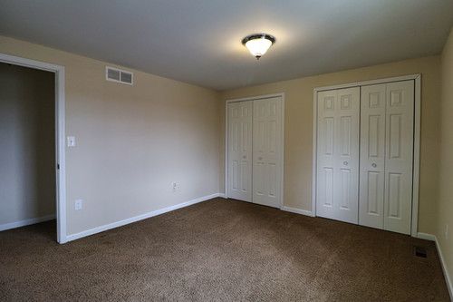 unfurnished bedroom with multiple closets, visible vents, baseboards, and dark colored carpet