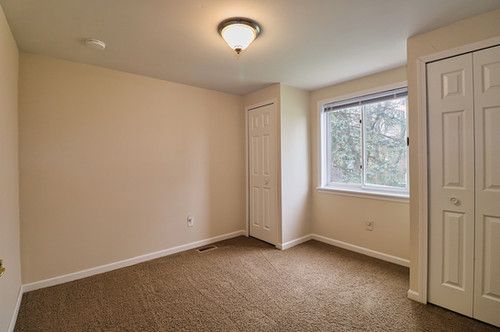 unfurnished bedroom with multiple closets, baseboards, visible vents, and dark carpet