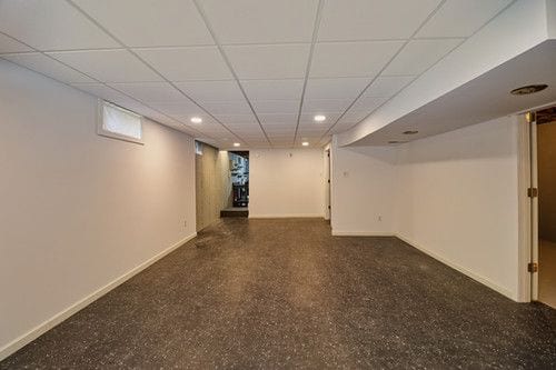 finished below grade area featuring baseboards, recessed lighting, and a paneled ceiling