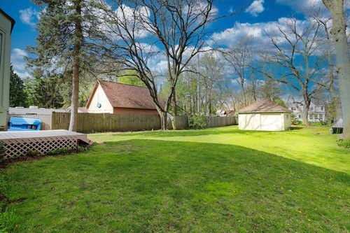 view of yard with a storage shed, an outbuilding, a fenced backyard, and a wooden deck