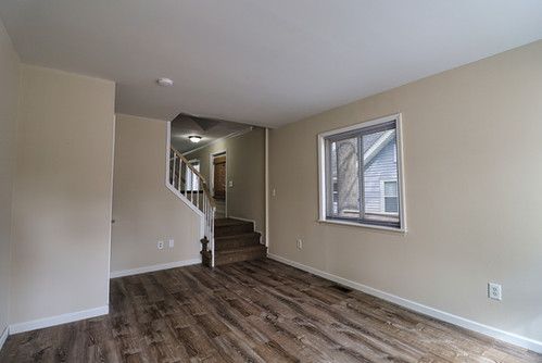 empty room featuring baseboards, wood finished floors, and stairway