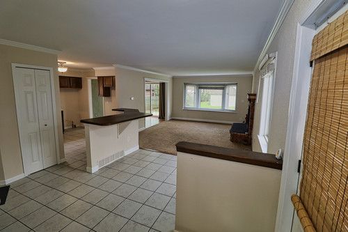 kitchen featuring a kitchen bar, dark countertops, light tile patterned floors, open floor plan, and ornamental molding