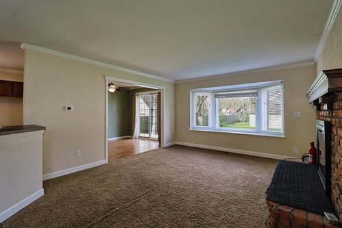 unfurnished living room with crown molding, baseboards, a fireplace, and carpet flooring