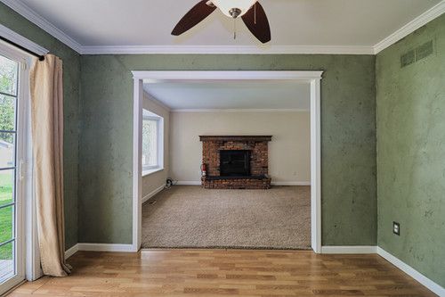 unfurnished living room with crown molding, ceiling fan, wood finished floors, and visible vents