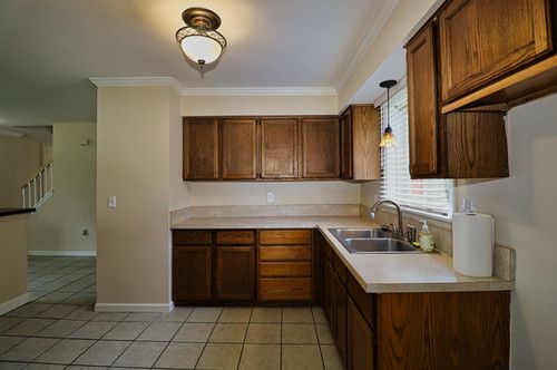 kitchen with a sink, light countertops, baseboards, light tile patterned floors, and ornamental molding