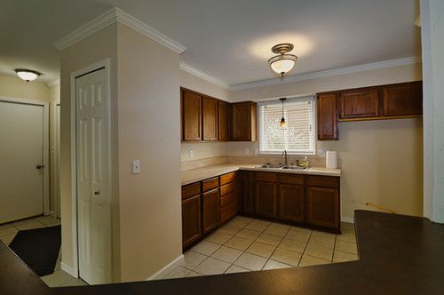 kitchen with crown molding, a sink, light countertops, baseboards, and light tile patterned flooring