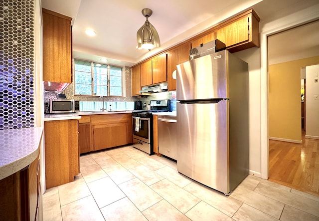 9186 Arnold St, Redford, MI 48239 - kitchen with stainless steel appliances, under cabinet range hood, light countertops, brown cabinets, and backsplash