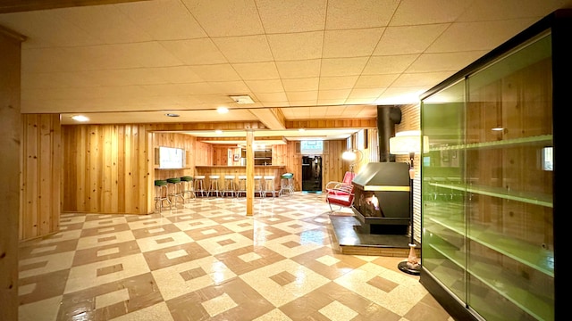 9186 Arnold St, Redford, MI 48239 - below grade area featuring a wood stove, tile patterned floors, wood walls, and bar area