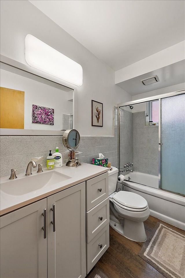 2180 Vernier Rd, Grosse Pointe Woods, MI 48236 - bathroom featuring tile walls, toilet, vanity, wood finished floors, and combined bath / shower with glass door