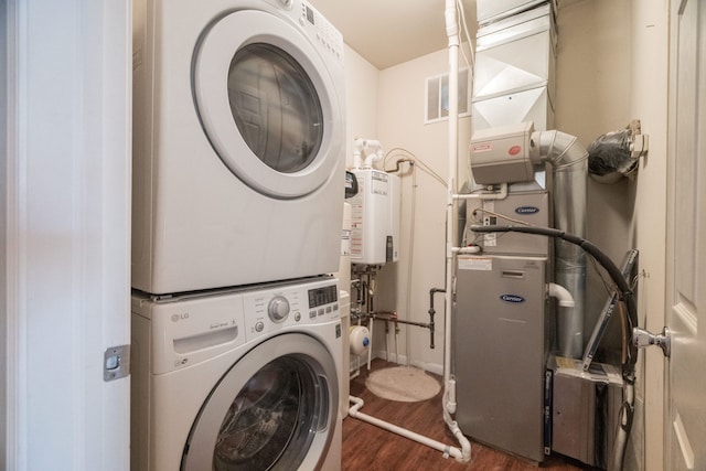 washroom with heating unit, visible vents, stacked washer and clothes dryer, dark wood-type flooring, and laundry area