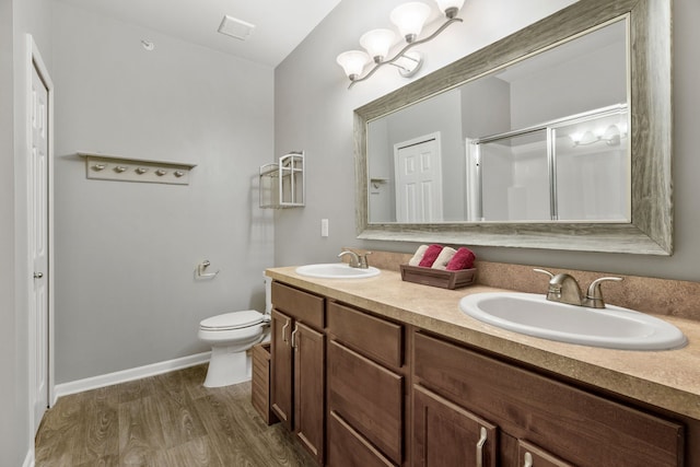 bathroom featuring wood finished floors, toilet, double vanity, an enclosed shower, and baseboards