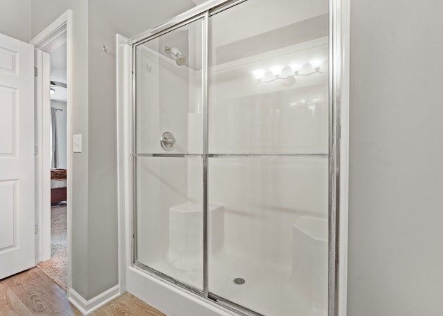 bathroom featuring a stall shower, wood finished floors, and baseboards