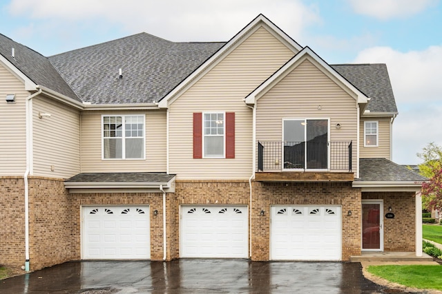 view of front of home featuring a balcony, a garage, brick siding, and driveway