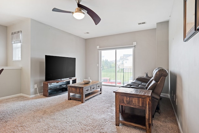 living room featuring visible vents, baseboards, a ceiling fan, and carpet floors