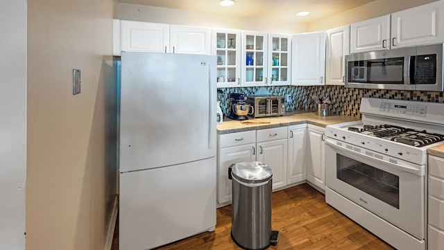 kitchen featuring white cabinetry, wood finished floors, and white appliances