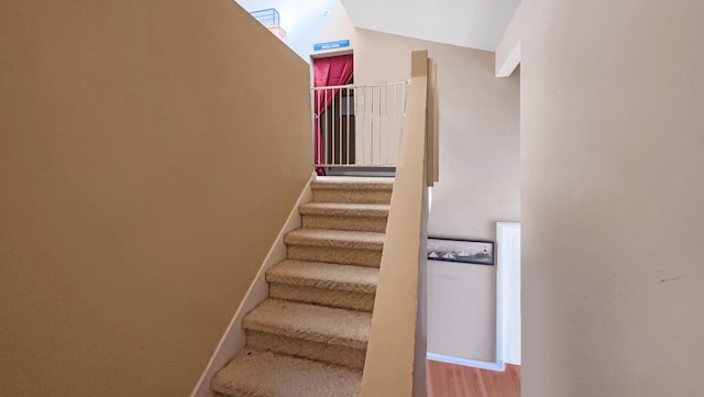 stairway featuring wood finished floors and lofted ceiling