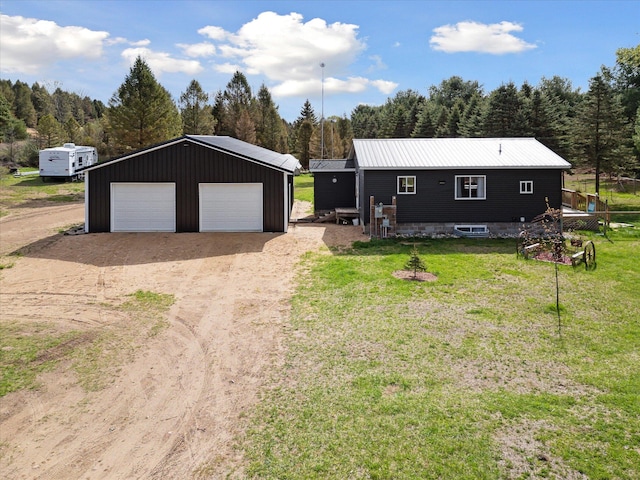 view of front of house featuring a garage, an outdoor structure, a front yard, and a forest view