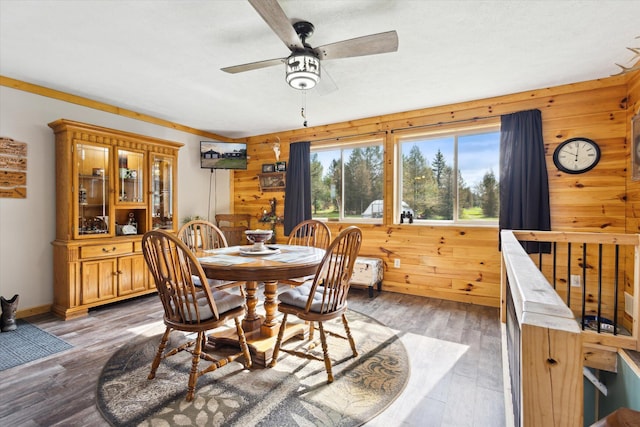 dining area featuring a ceiling fan, wood walls, and light wood-style floors
