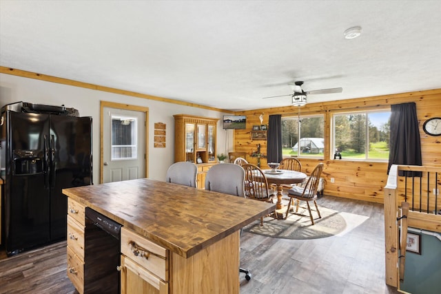 kitchen featuring wood counters, wood walls, black refrigerator with ice dispenser, a ceiling fan, and dark wood-style floors