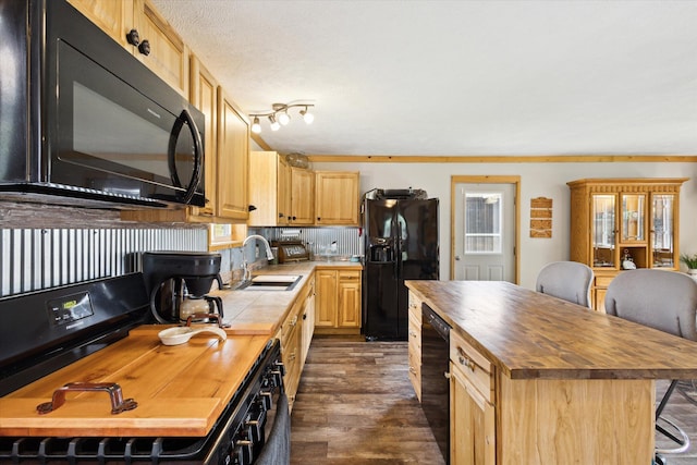 kitchen featuring light brown cabinetry, a sink, butcher block countertops, dark wood-type flooring, and black appliances