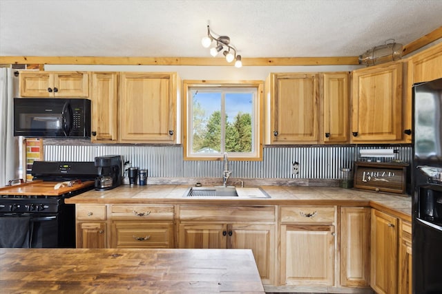 kitchen with a sink, light brown cabinets, a textured ceiling, tile countertops, and black appliances