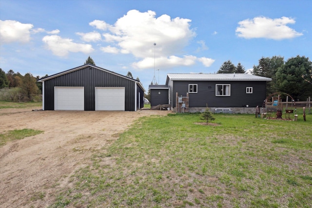 view of front of home featuring metal roof, an outdoor structure, a front yard, and a garage