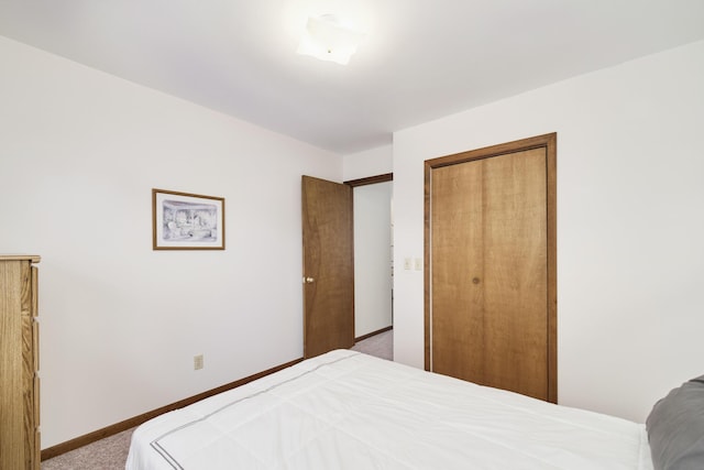 carpeted bedroom with baseboards and a closet