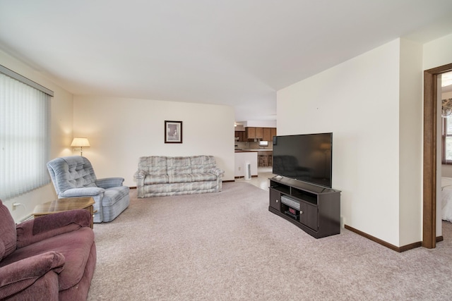 living area with baseboards, light carpet, and a healthy amount of sunlight