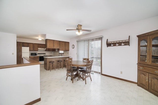 dining area with a ceiling fan and baseboards