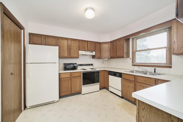 kitchen with light countertops, a sink, under cabinet range hood, and white appliances
