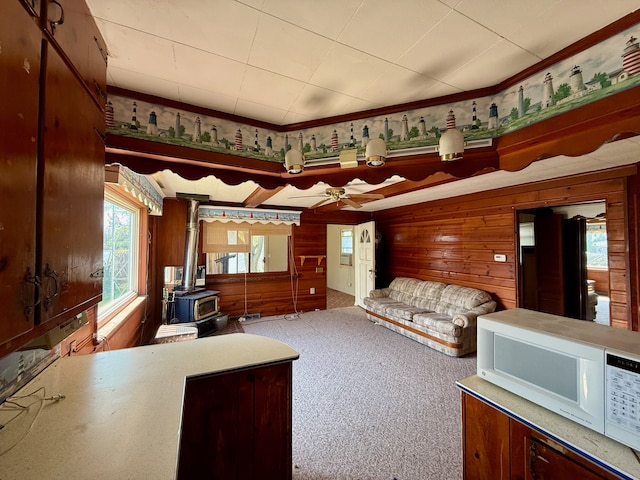 2964 Morin Point St, Erie, MI 48133 - living area featuring carpet flooring, a ceiling fan, wood walls, a wood stove, and ornamental molding