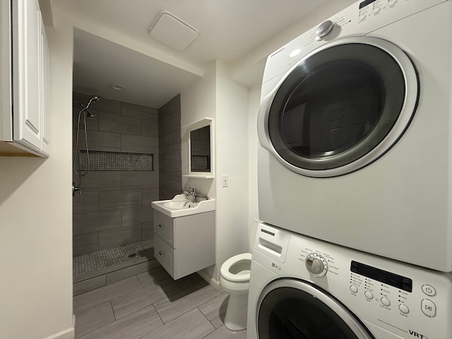 5781 Wright Dr, Troy, MI 48098 - clothes washing area featuring stacked washer and clothes dryer, baseboards, and wood tiled floors